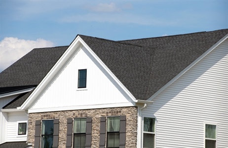 Edge of black shingle roof on white home.