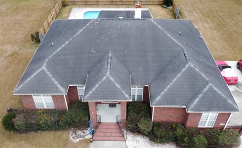 Aerial view of brick home with black, storm damaged roof.