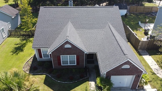 Aerial view of two story brick home with black roofing.