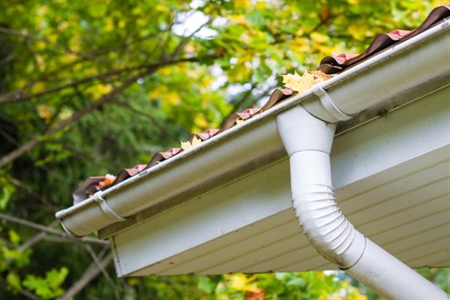 Close up of white gutter system with downspout.