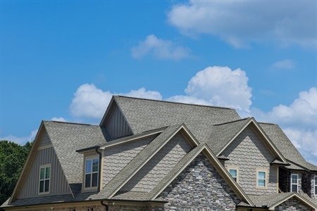 Upper half of brown and gray home with gray roofing.